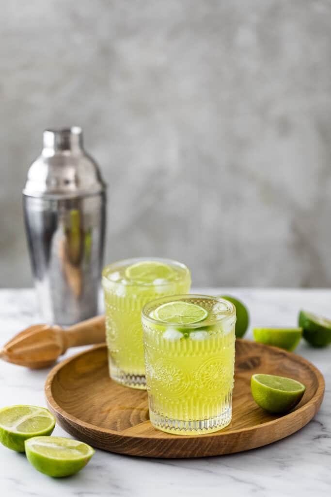 two glasses filled with tokyo tea on marble background with silver cocktail shaker