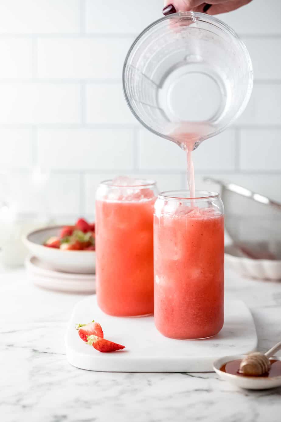 pouring strawberry water into two large glasses