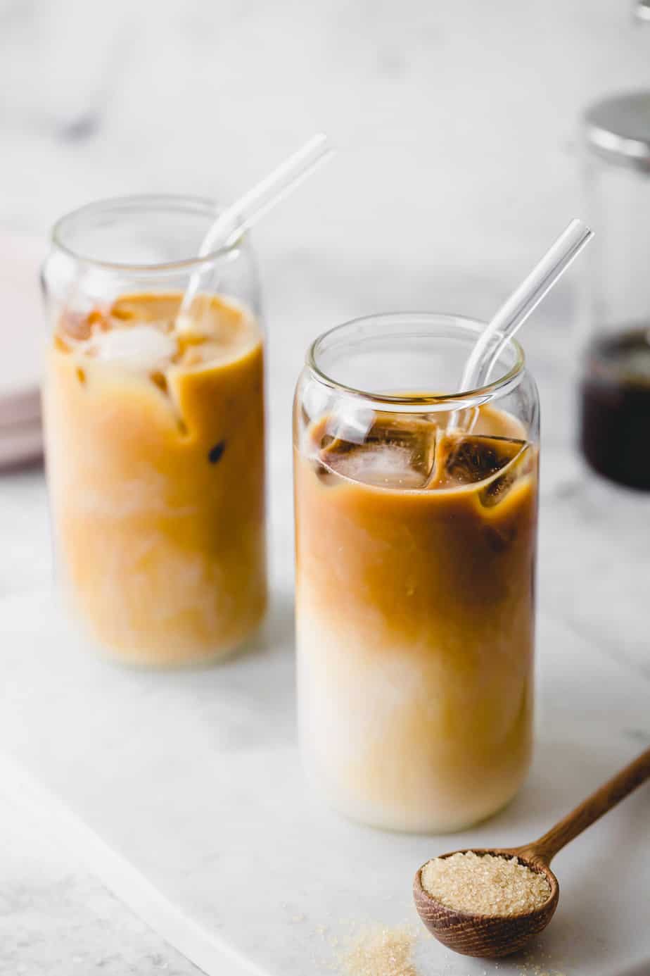 Two decaf cold brew iced coffees in tall glasses with glass straws.