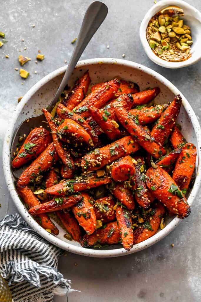 carrots in white bowl with a spoon and striped cloth