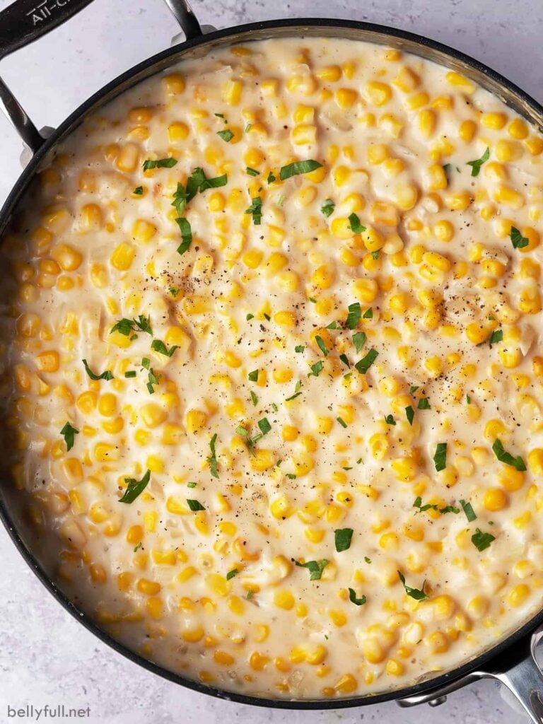 creamed corn in pot with fresh herbs