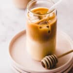 homemade starbucks honey almond milk cold brew latte on pink plates with honey swizzle stick
