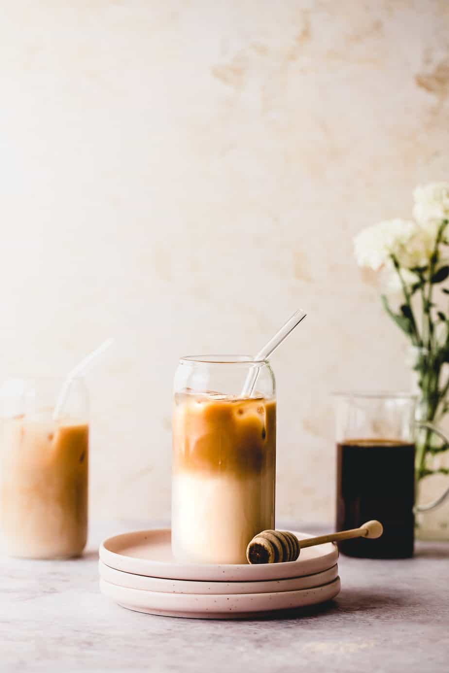 Three iced coffees on a marble counter in glasses.