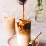 cold brew coffee in glass jug pouring into tall glass with almond milk