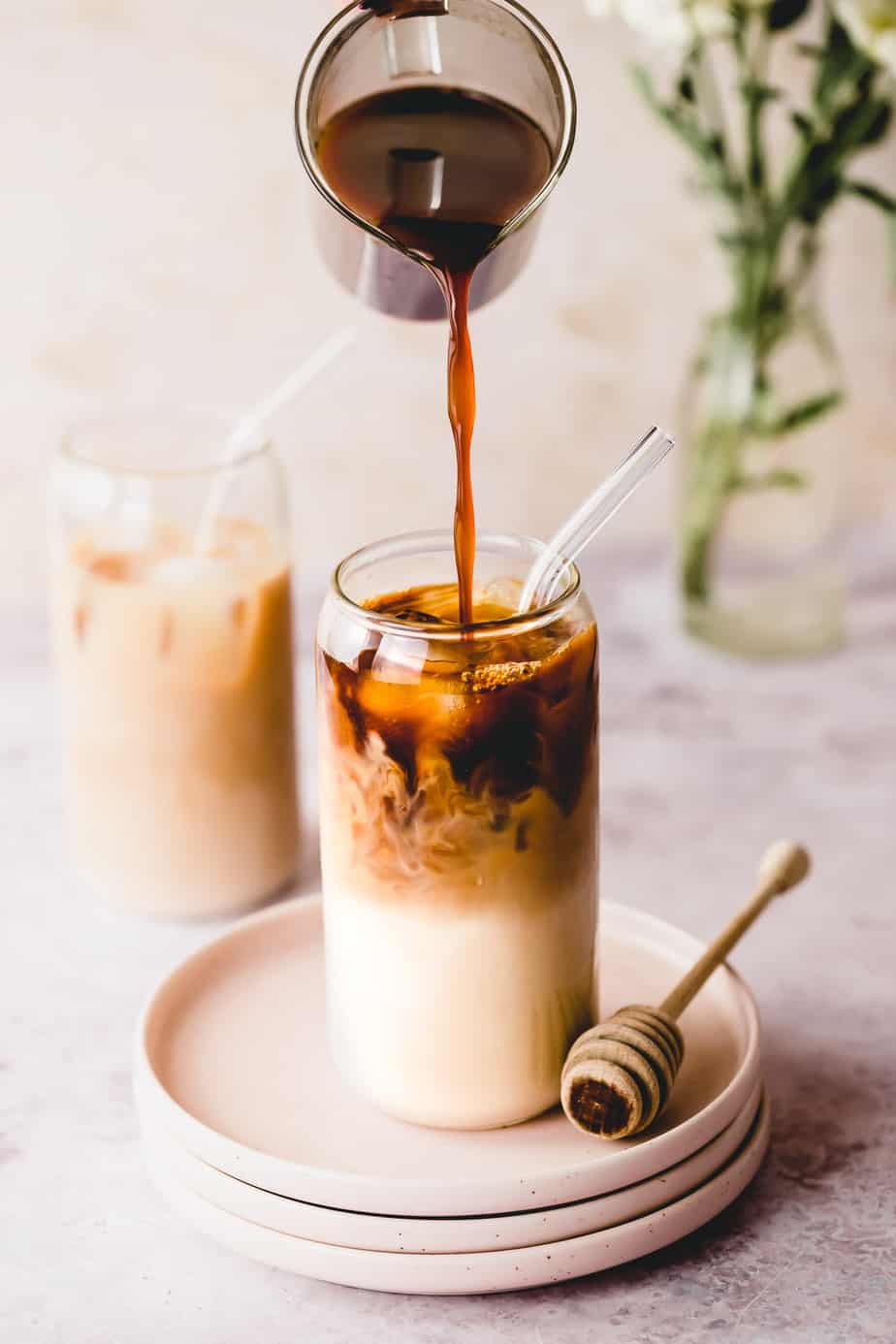 cold brew coffee in glass jug pouring into tall glass with almond milk