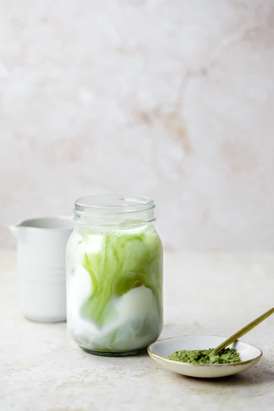 A matcha latte swirled into milk with ice cubes.