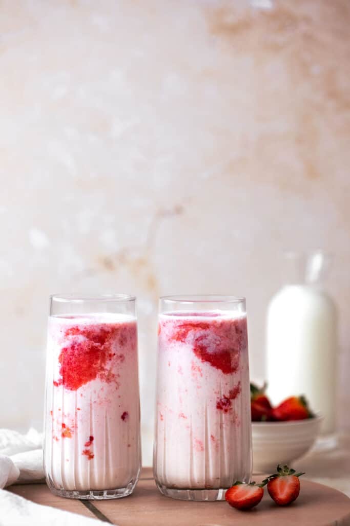 two glasses filled with korean strawberry milk on pink marble