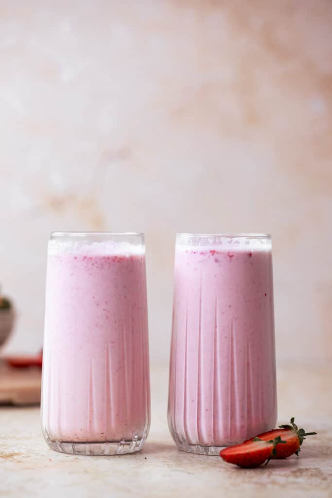 korean strawberry milk with pink background and fresh strawberries cut in half