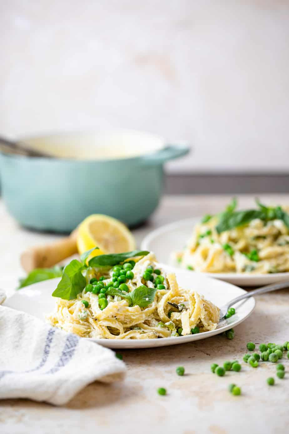 Lemon and Ricotta Cheese Pasta in a bowl garnished with fresh basil and peas.