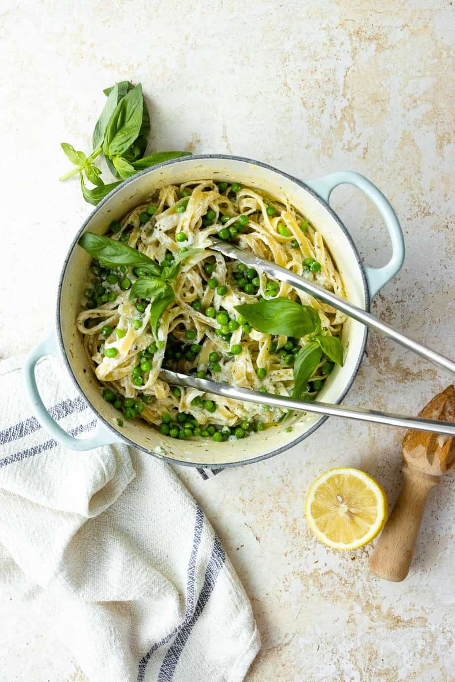 A pot full of Fettuccine Alfredo with serving tongs.