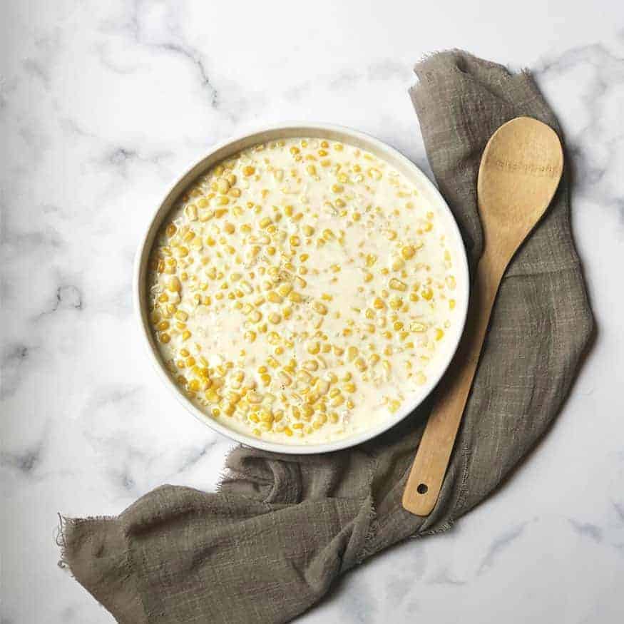 creamed corn in white bowl on marble background
