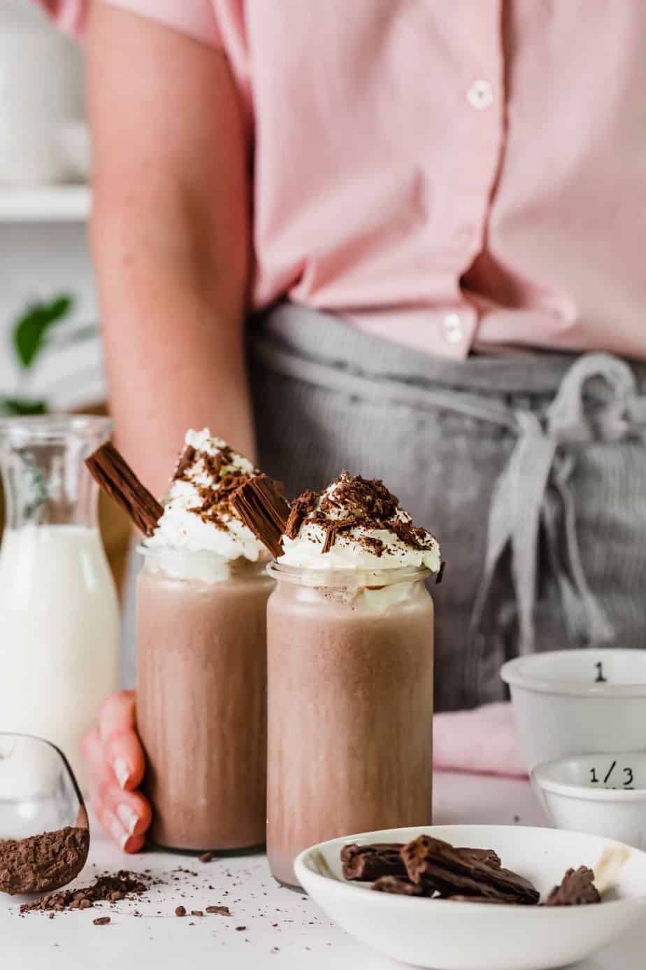 Two shakes topped with cream in serving glasses with chocolate and brownie bits.