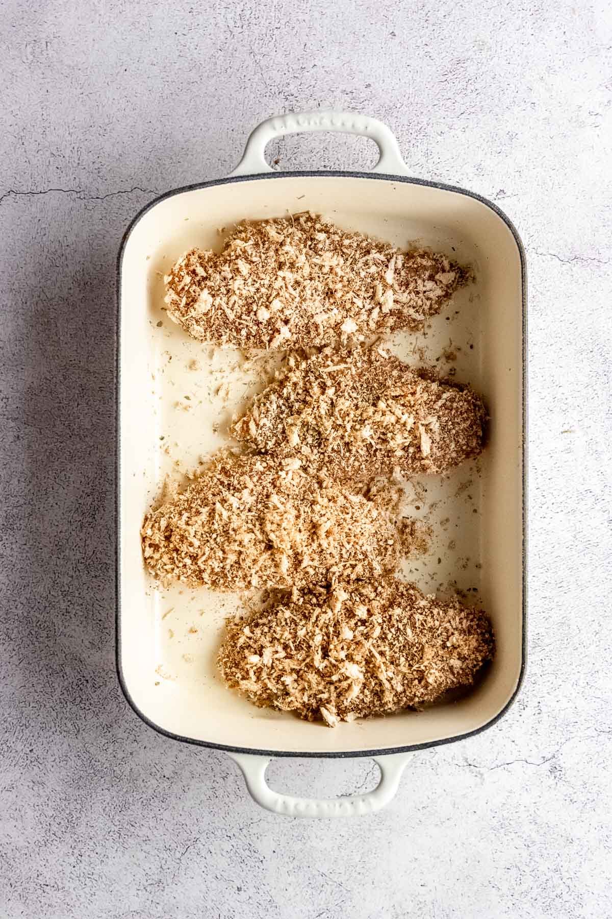 Panko coated chicken in a baking dish.