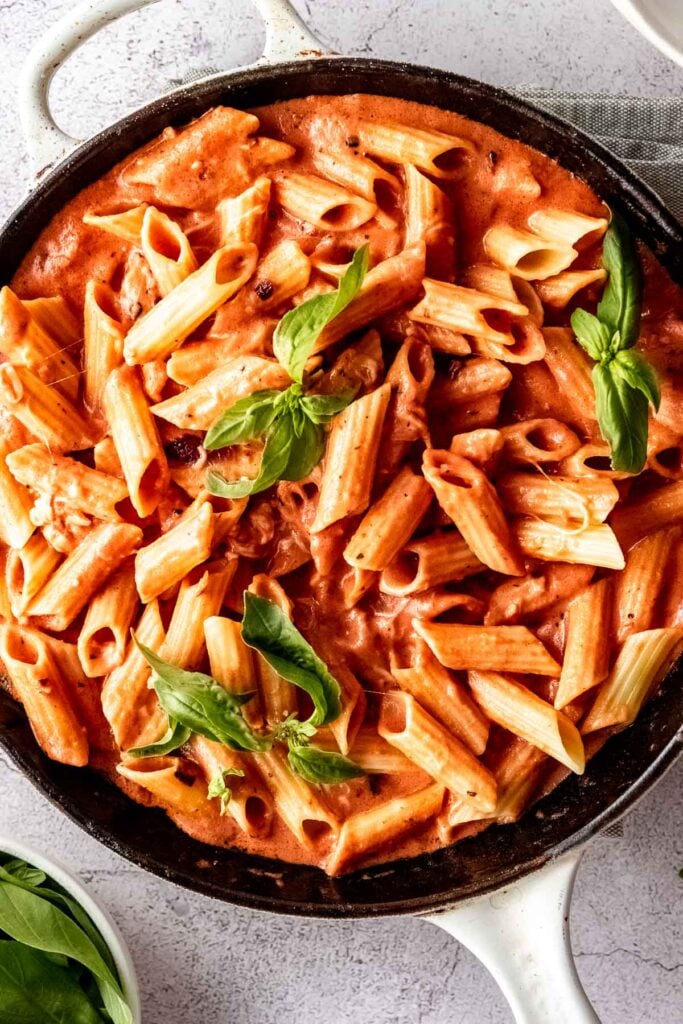 pink sauce pasta in white skillet with fresh basil
