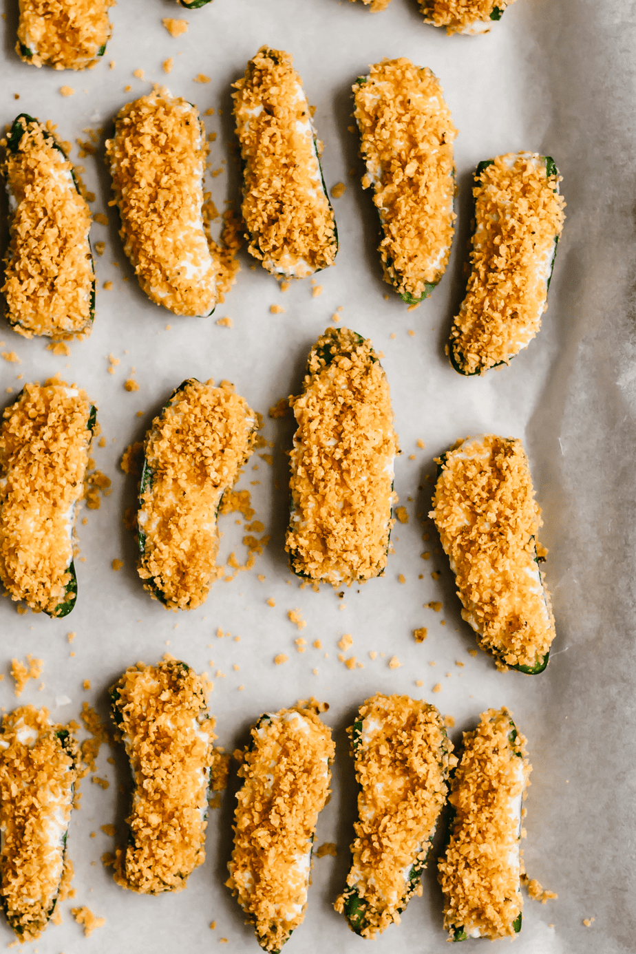 Jalapeno poppers on a baking tray that have a tortilla chip crust.