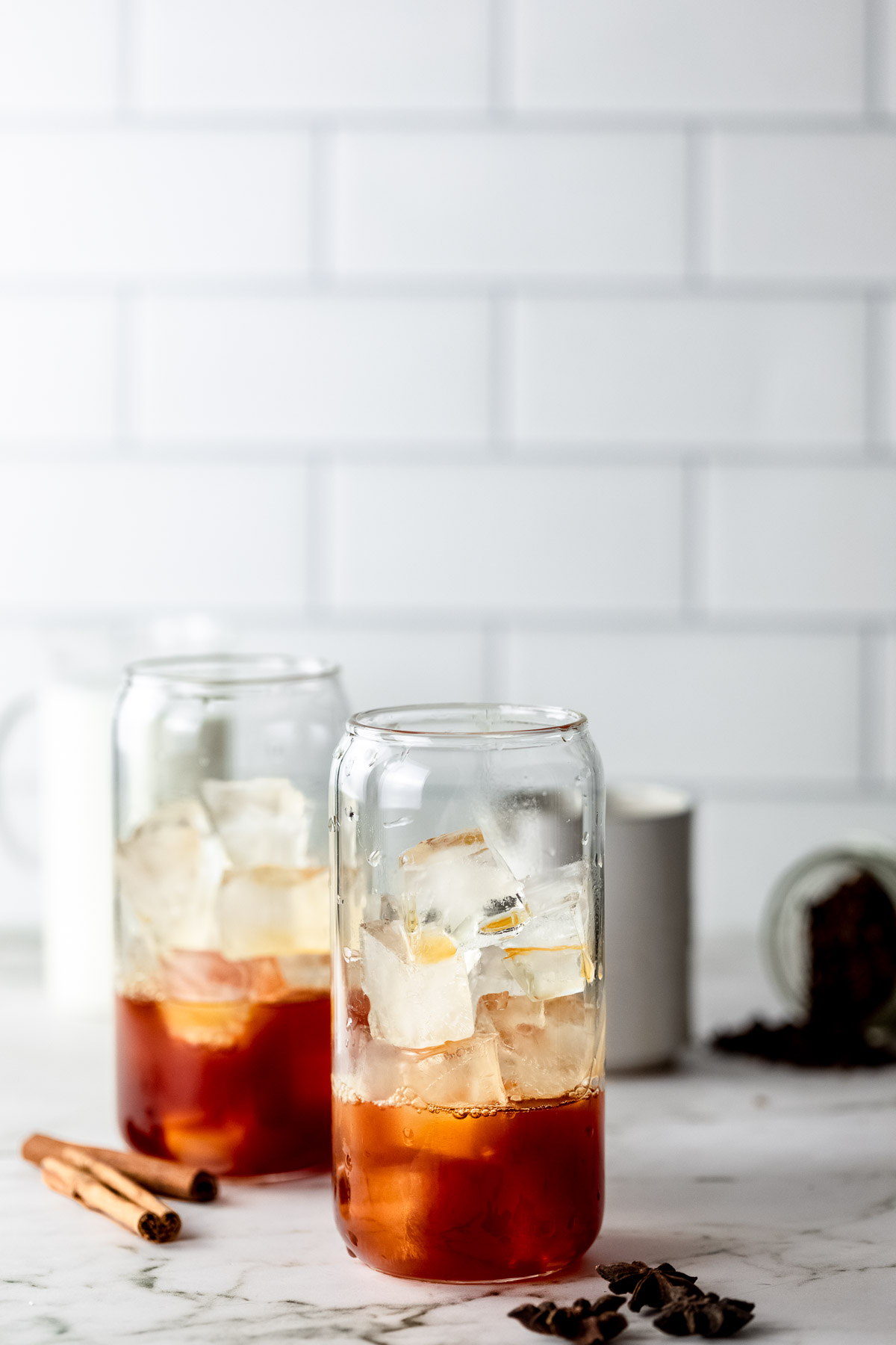 Chai tea in serving glasses with ice and whole spices.