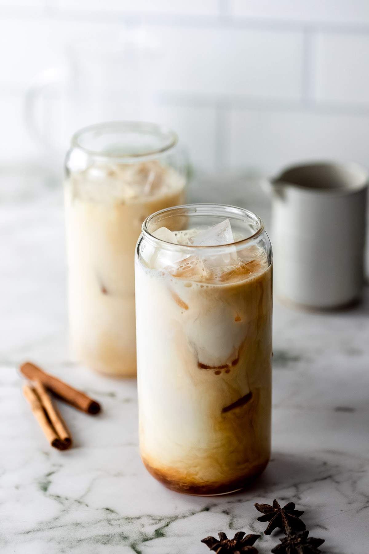 A glass of iced masala chai tea with whole spices.