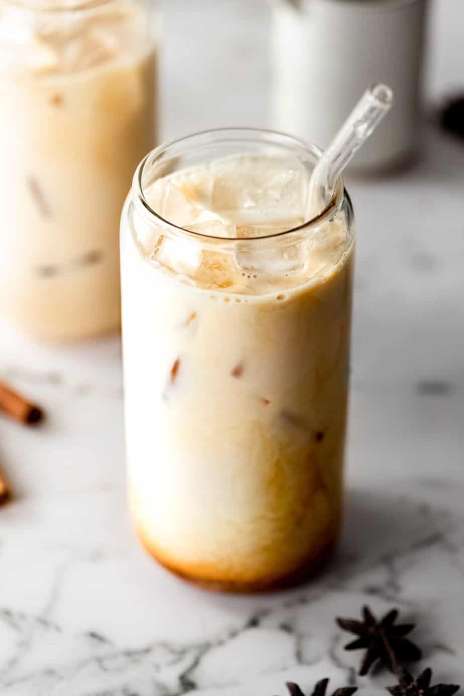 An Iced Dirty Chai Latte with ice cubes and whole dried spices.