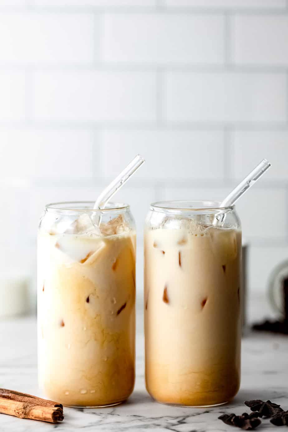 Two dirty chai iced coffees in serving glasses with glass straws.