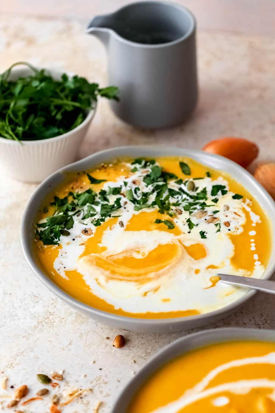 A bowl of soup with a drizzle of cream and fresh herbs on top.