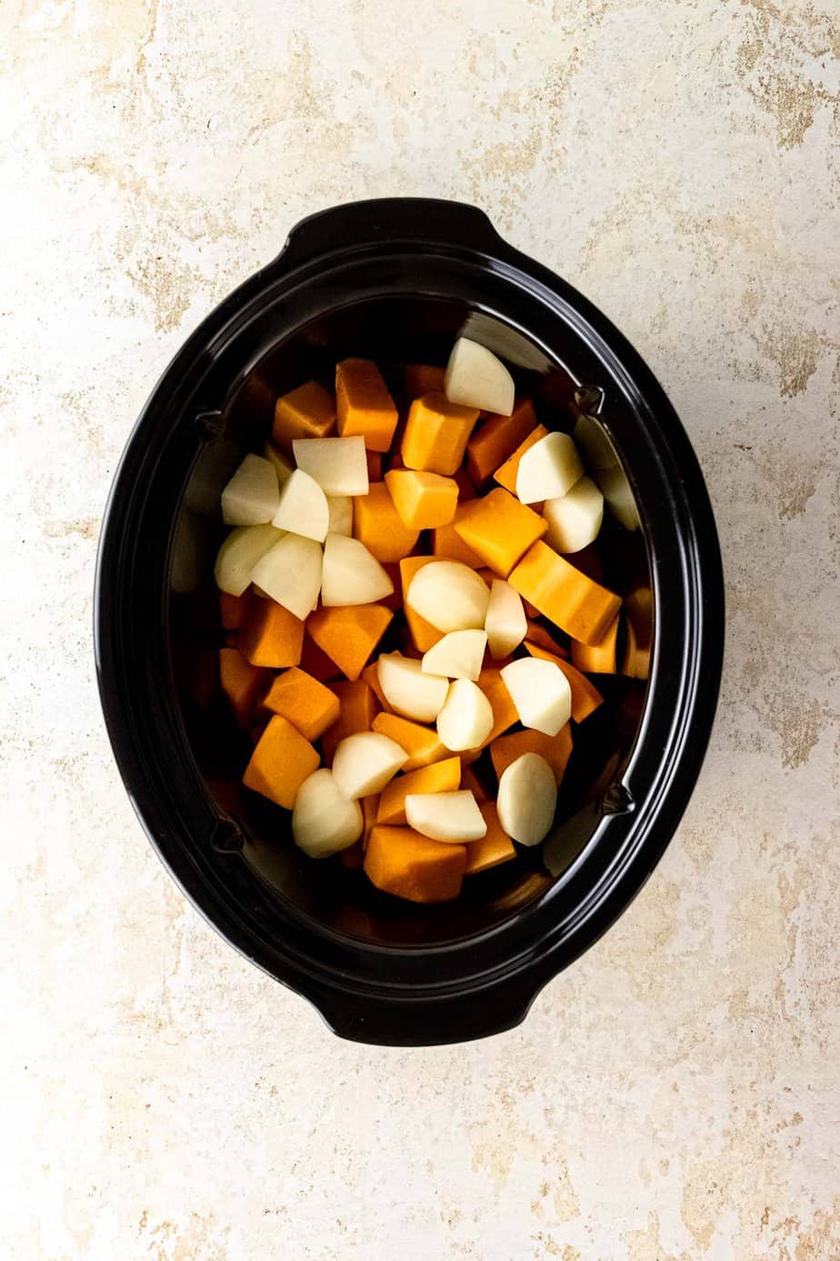 Chunks of pumpkin and potato in a slow cooker.