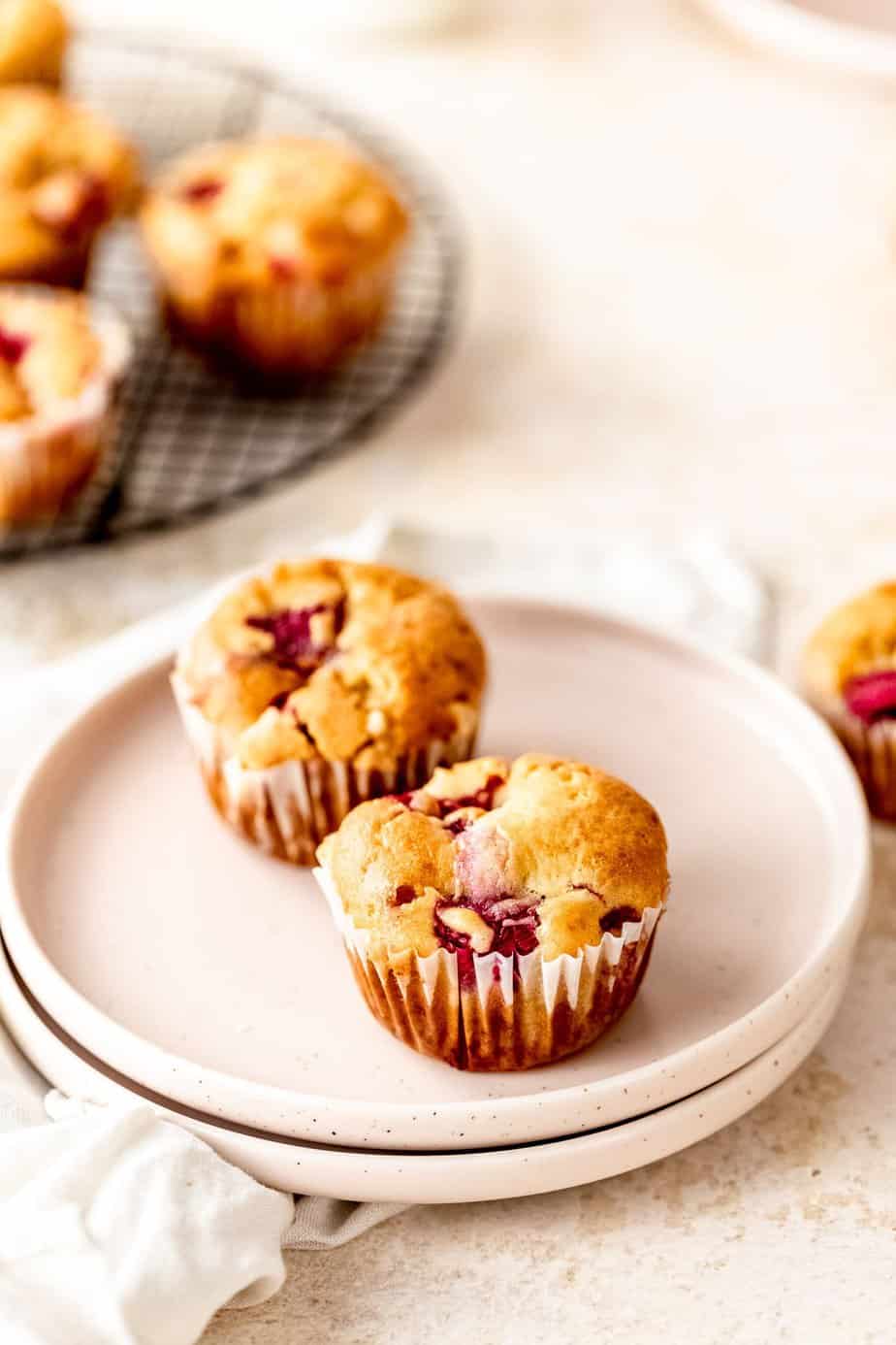 Two raspberry muffins on a small white plate.