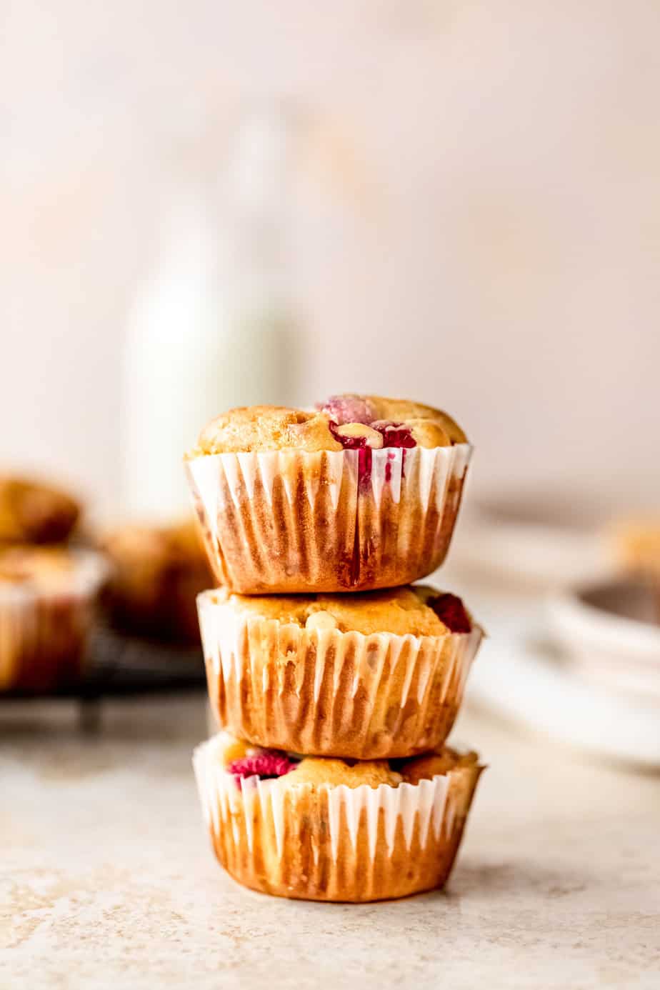 Three raspberry muffins stacked on top of each other.