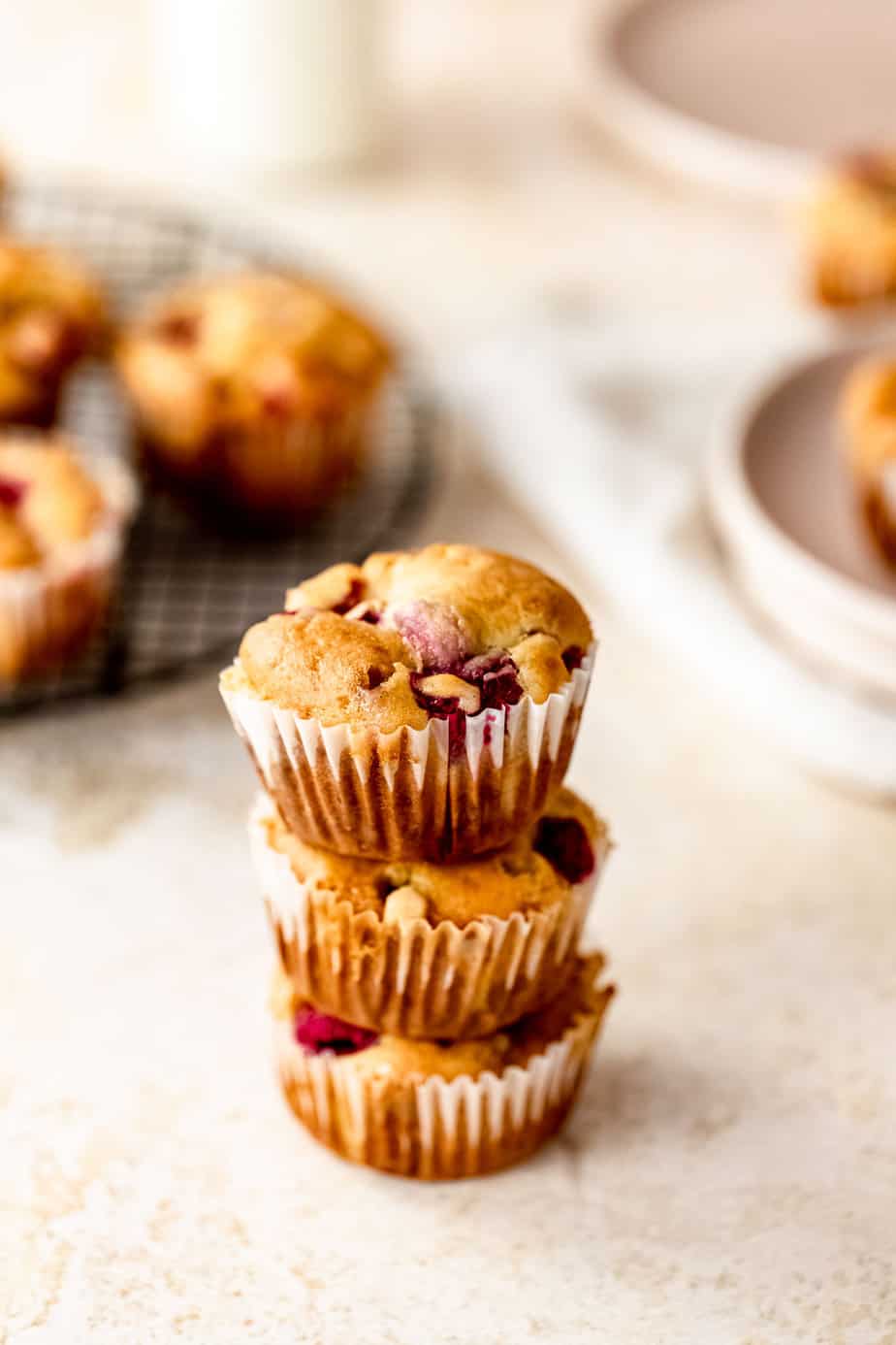 Three muffins stacked on top of each other with a few more in the background.