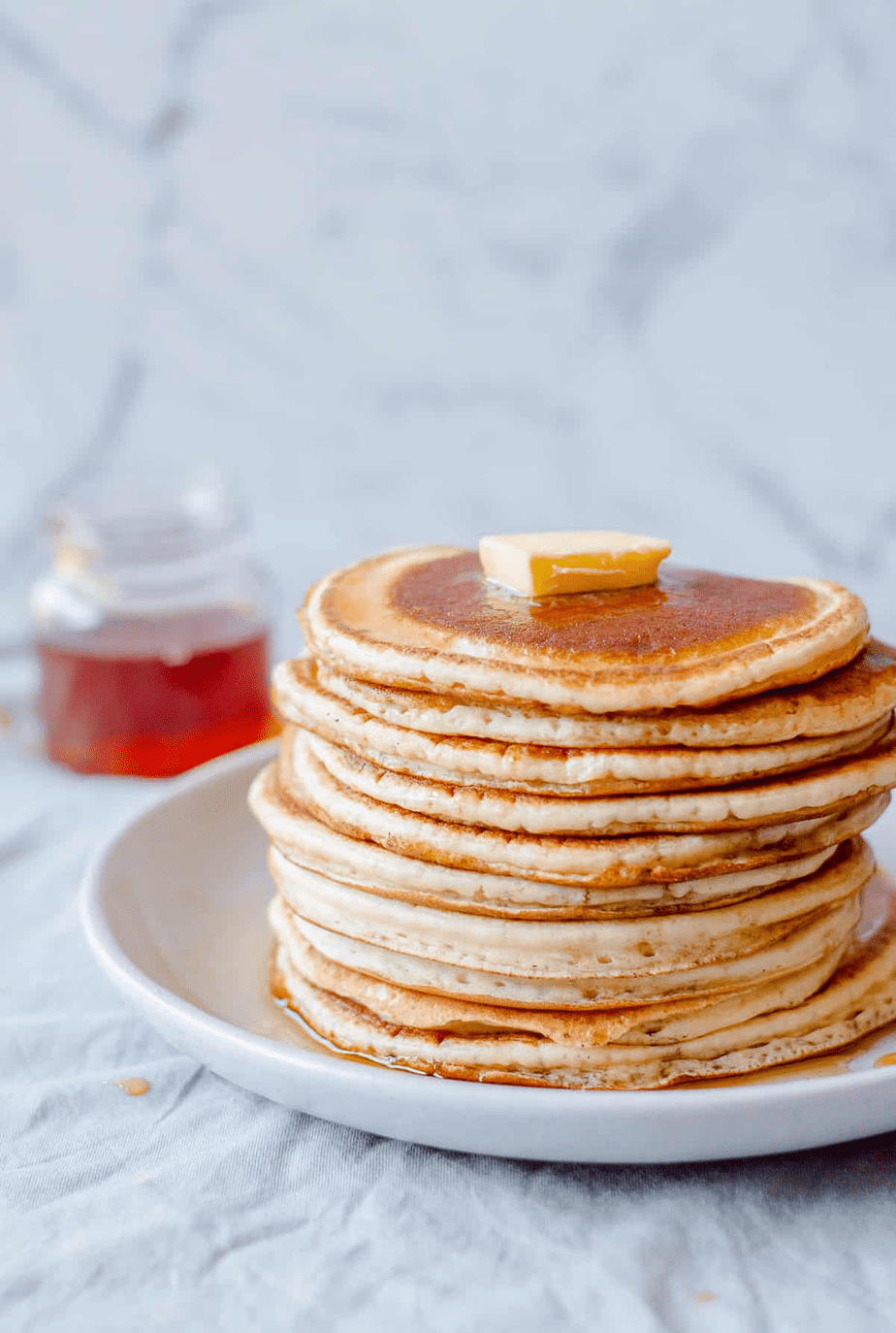 A stack of pancakes with a cube of butter on top.