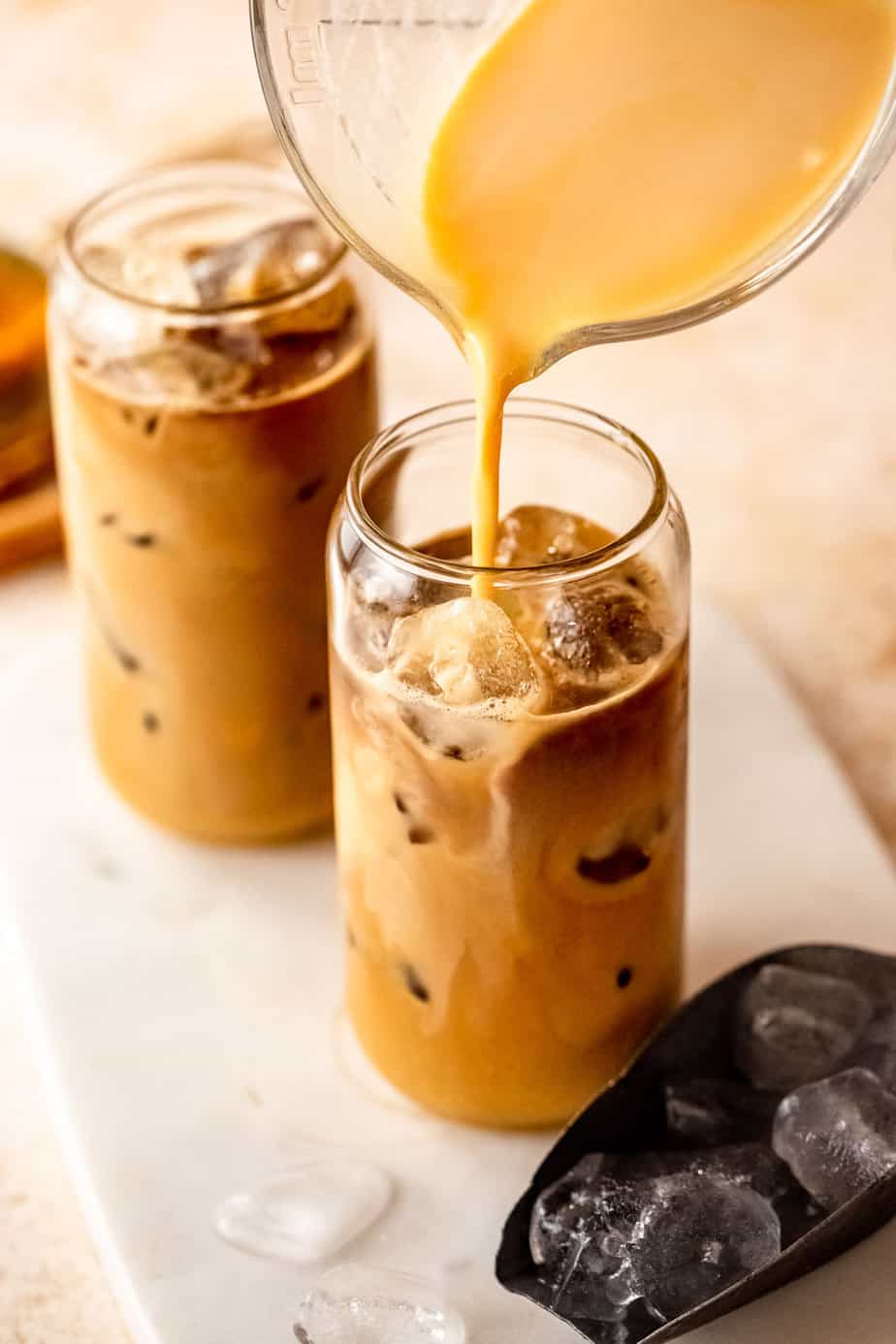 Iced Pumpkin Chai Latte pouring into a glass filled with ice cubes.