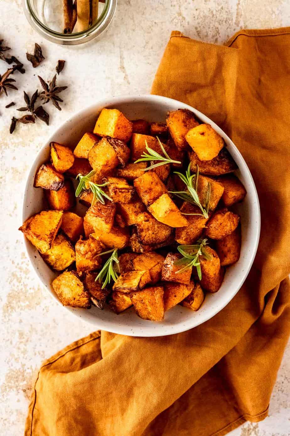 A white bowl of roast pumpkin with a linen cloth.