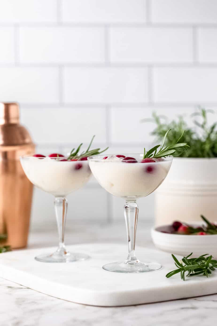 A christmas cocktail with fresh cranberries. and rosemary in stemmed glass serving glasses
