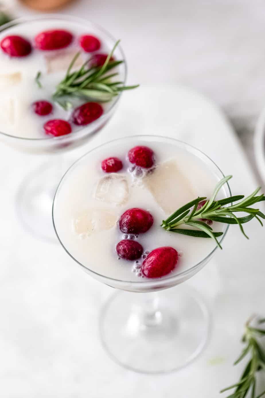 A christmas cocktail with fresh cranberries and rosemary sprigs.