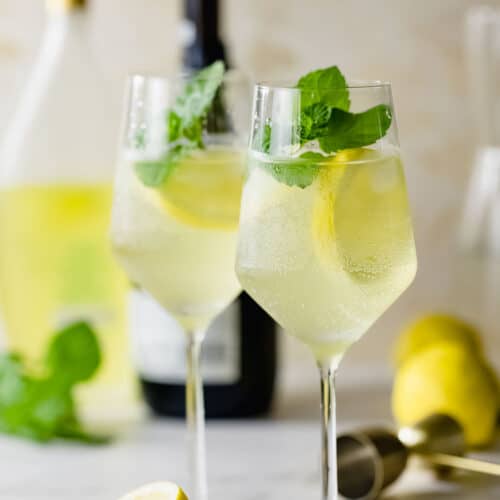 wine glasses filled with limoncello spritz and fresh mint sprigs