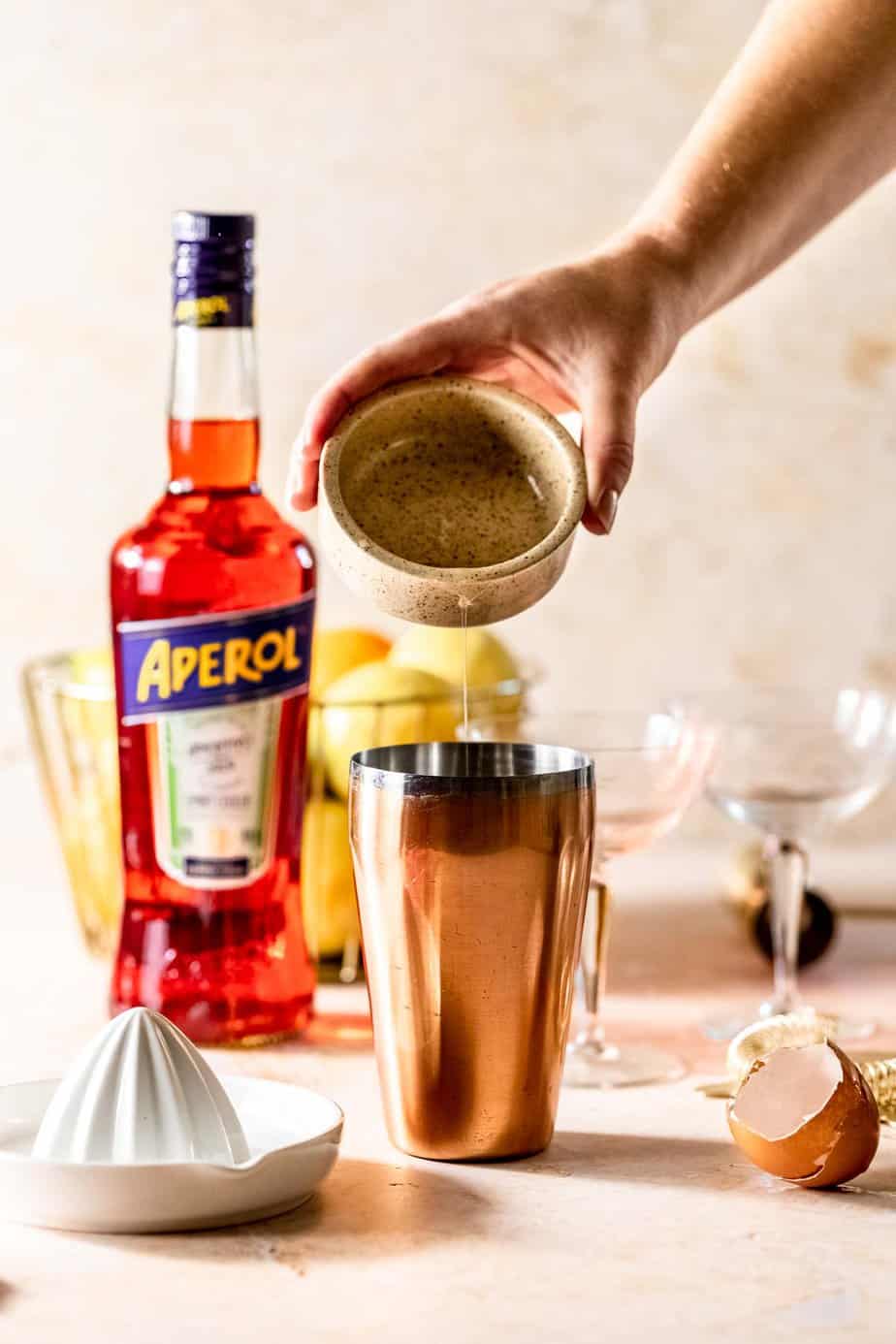 A cocktail being made with a bottle of Aperol