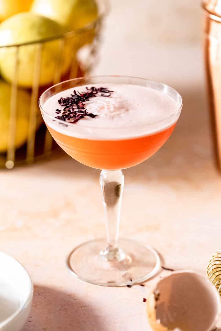 aperol sour on pink background with lemons