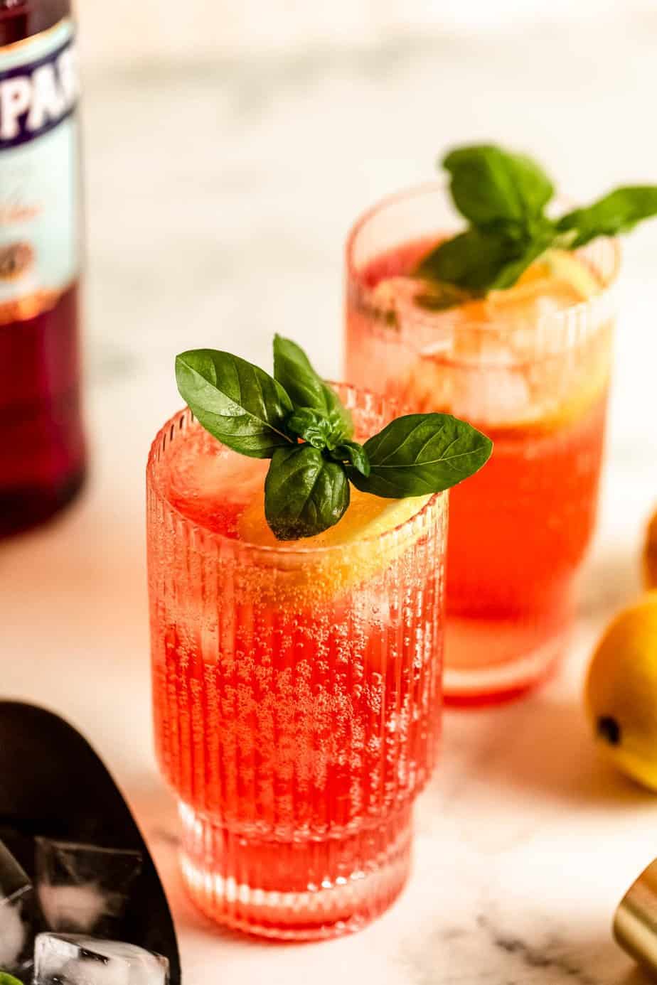 campari soda in two ribbed glasses with fresh basil