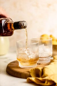 whiskey pouring into glass over ice