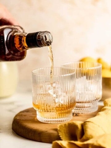 whiskey pouring into glass over ice