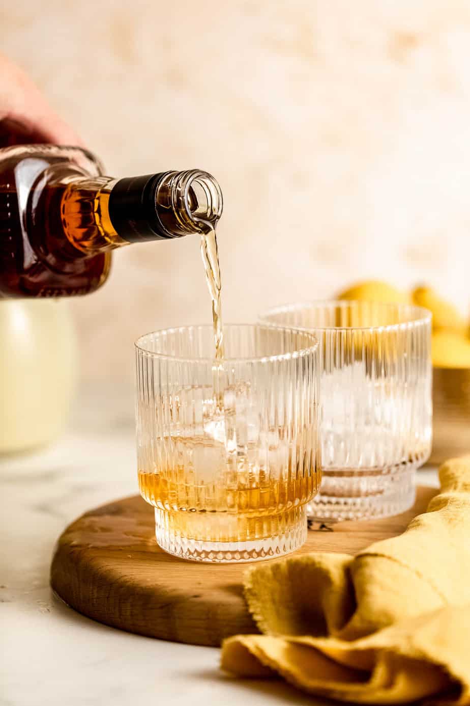 Dark liquor pouring into ribbed glass over ice