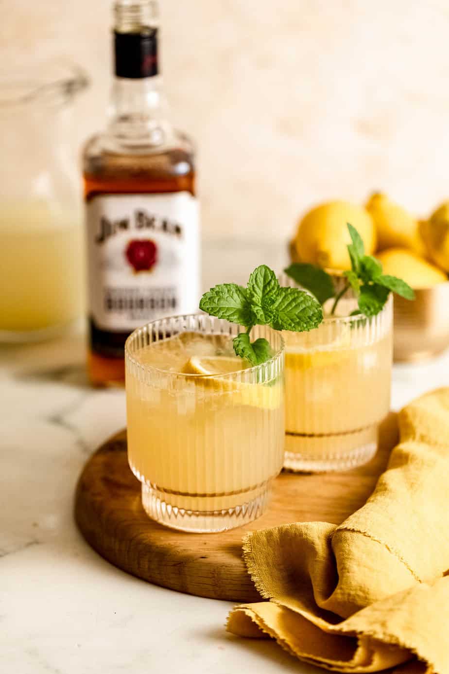 bourbon lemonade on wooden board with bourbon bottle in background