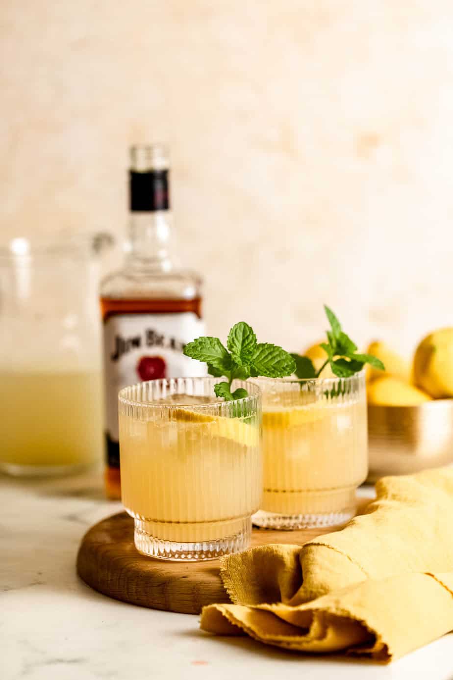 Whiskey cocktails in serving glasses with fresh mint and lemons.