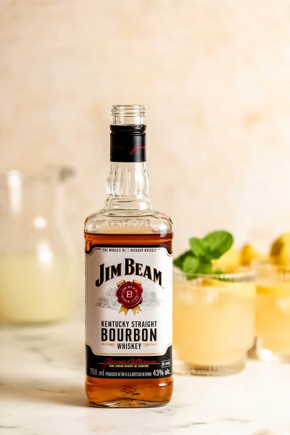 bottle of jim beam bourbon with bourbon lemonade cocktails in the background