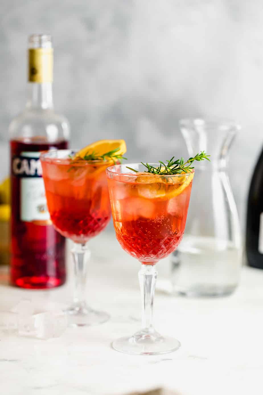 camapri spritz in two tall glasses with campari bottle in background