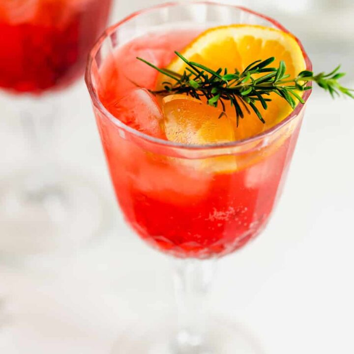 campari spritz in glasses with fresh orange slices and rosemary sprigs