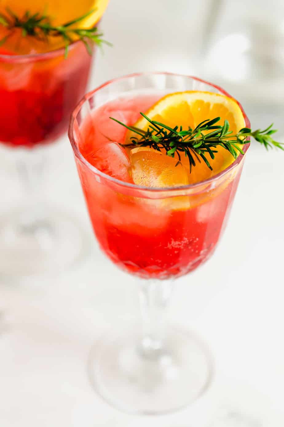 campari spritz in glasses with fresh orange slices and rosemary sprigs