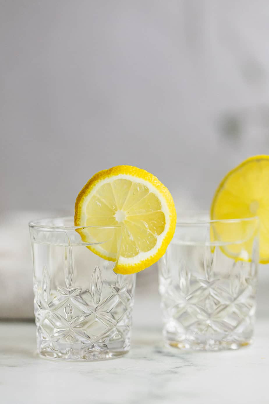 two shot glasses filled with vodka and topped with lemon slices
