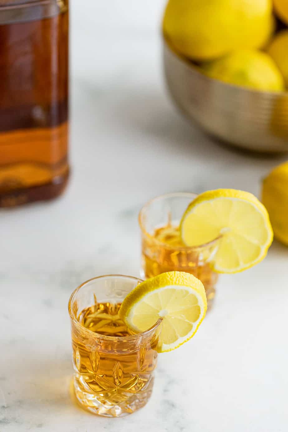 Whiskey in two shot glasses with lemons