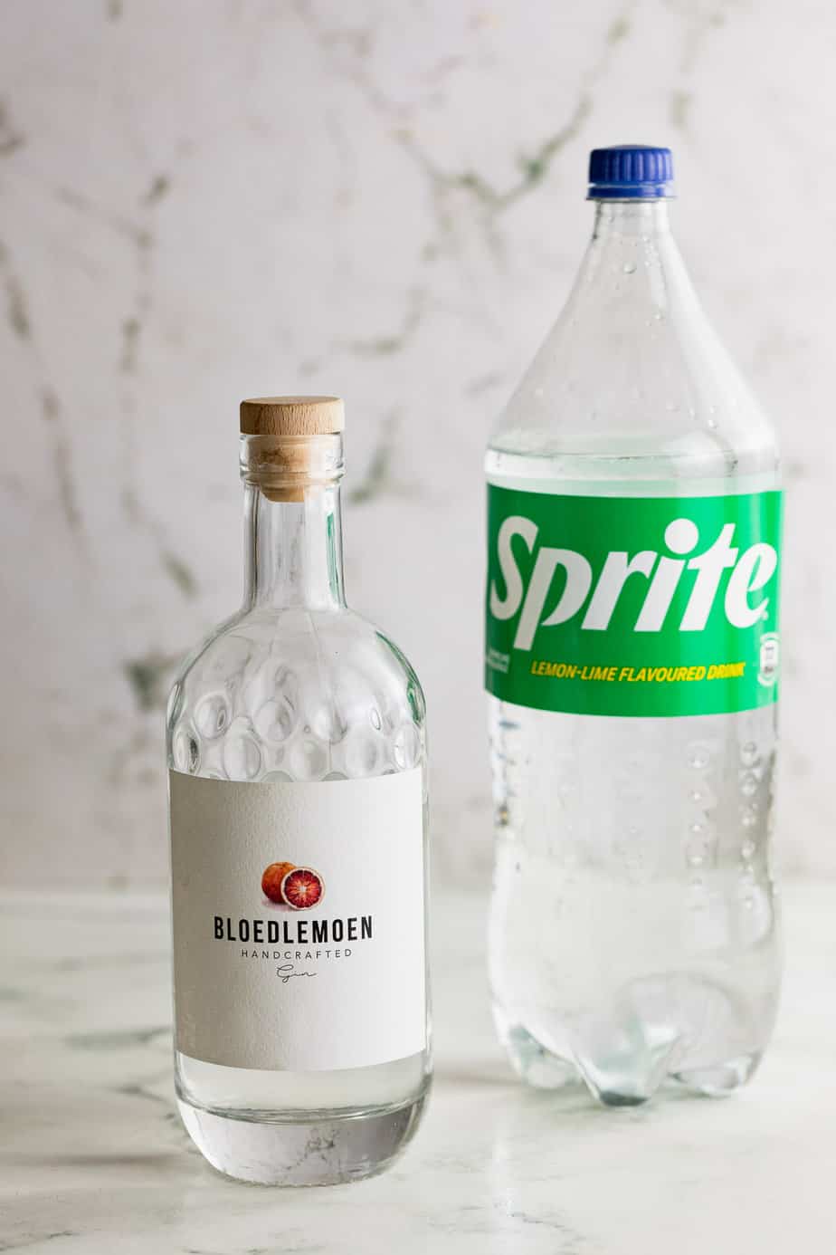 bottle of gin and bottle of sprite on marble