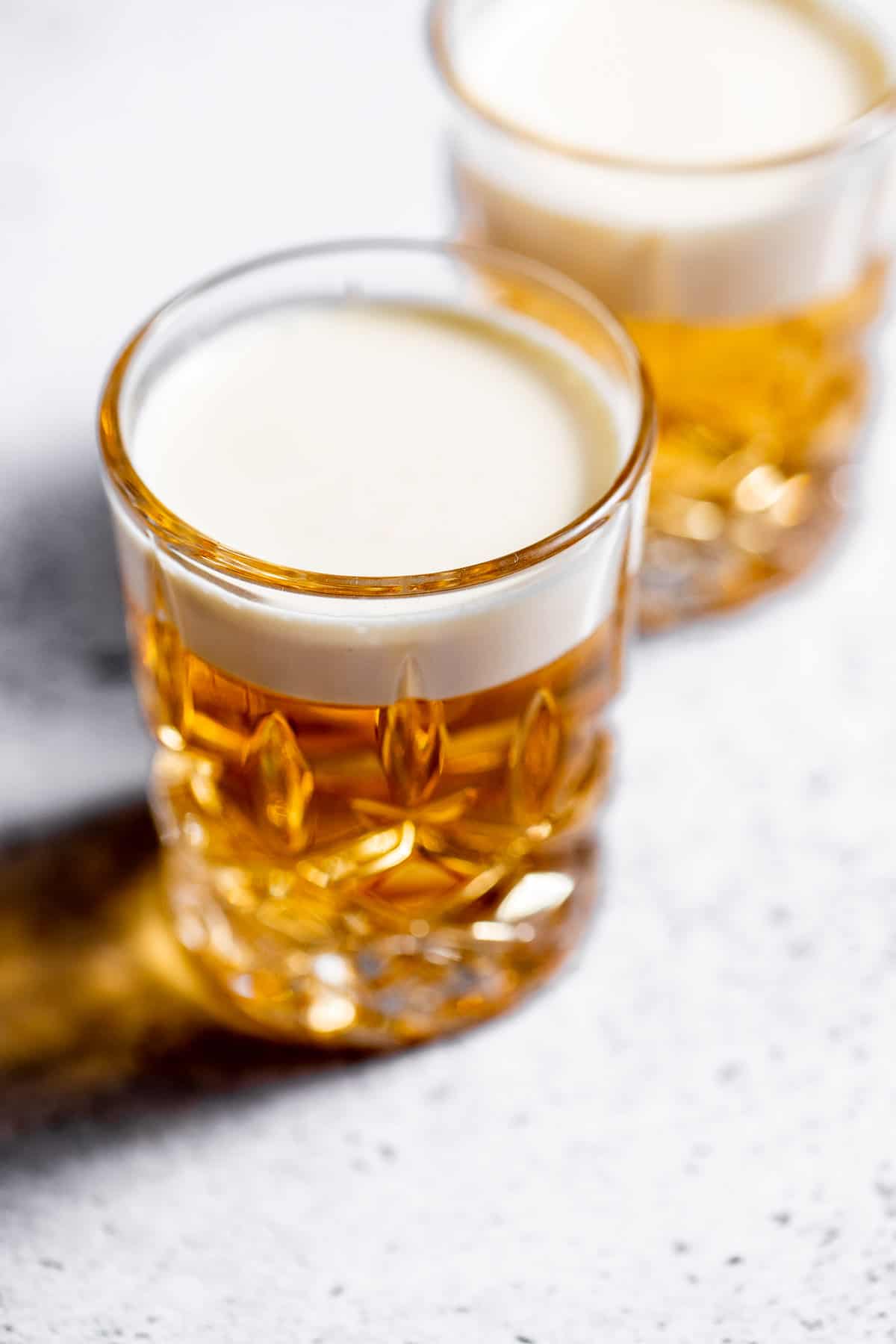 Two layered Mini Beer Shots on marble background with heavy cream topping.